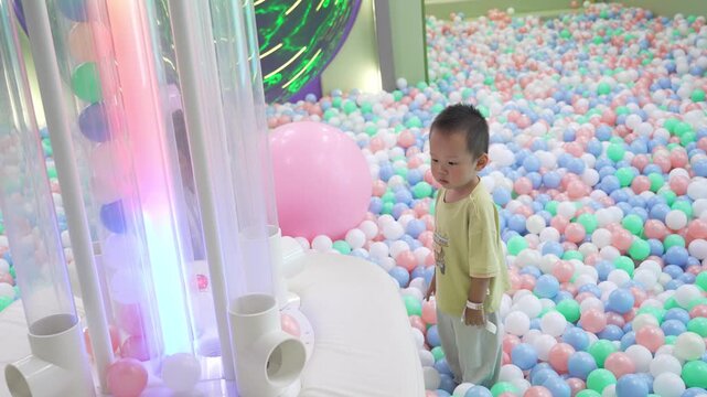 Full-length view of toddler playing beside illuminated ball pit tubes