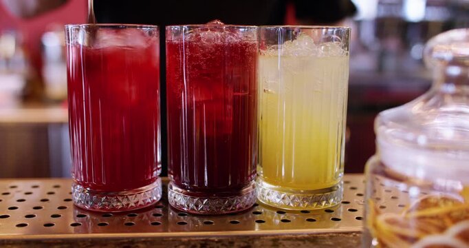 Stirring cocktail. Ice cube beverage. Barman hand making cold aperitif glass on counter. Man mixing sparkling water with color aroma juice.