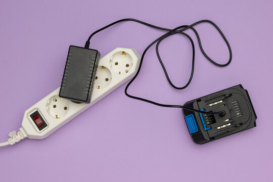 Efficient Power Solution: Plugged Extension Cord and Battery Charger on Purple Background