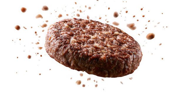 A single cooked beef patty floating in midair with flying crumbs