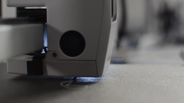 Macro shot of a 3D printer printhead extruding white plastic layer onto a heated bed