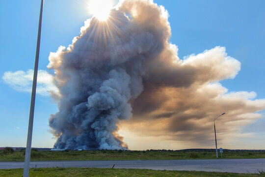 Smoke from a fire rises into the sky. Thick smoke obscures the sky and sun in rural areas.