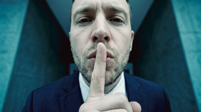 Businessman holding finger to lips in silence gesture