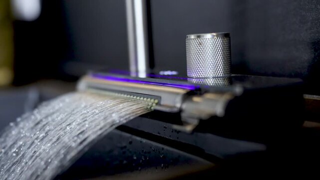 Close-up cinematic footage of a modern faucet with water flowing in a contemporary interior. The sequence shows the faucet being turned on, water running steadily, being turned off.