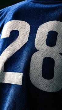 A close view of a sports jersey with the number 28 displayed in vertical format on the back, set against a dark background.