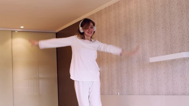 Carefree routine. Music morning. Happy playful woman in modern headphones enjoying joyful mood positive atmosphere at home interior.