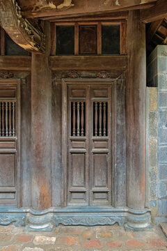 Traditional wooden door and window panels with intricate carvings of an ancient pagoda temple in Ninh Binh, Vietnam