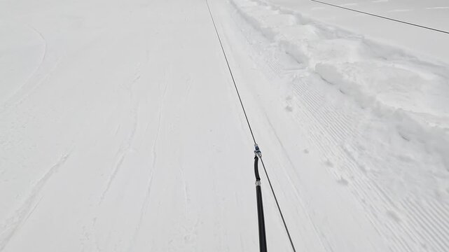 美しい圧雪バーンを滑走式リフトで登るスキーヤーの足元主観映像（POV）
