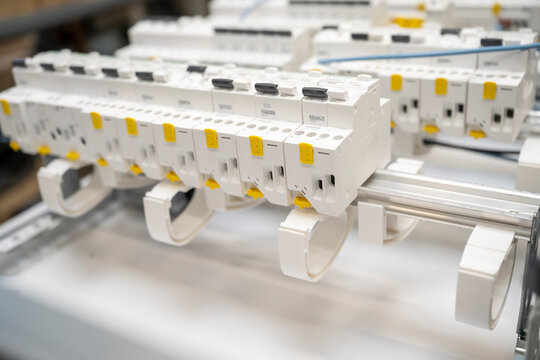 Close-up of white modular circuit breakers installed in an electrical panel, with yellow switches and labels visible.