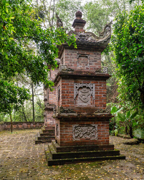 Intricate ancient brick stupa with stone carvings in the lush, serene forest setting of the Bai Dinh Pagoda complex, Ninh Binh, Vietnam
