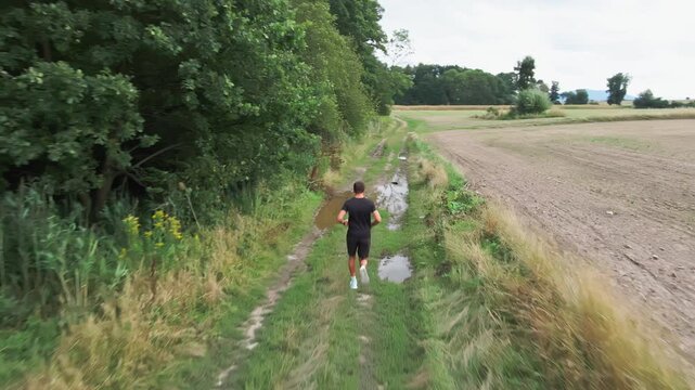 Man running on muddy country road during outdoor workout