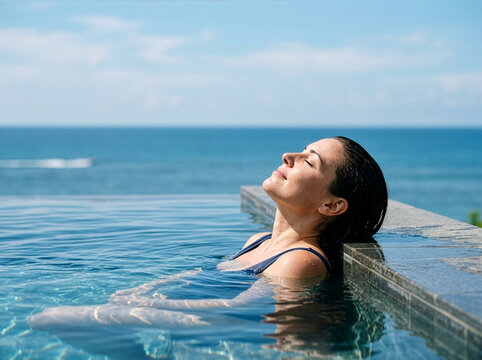 Woman Relaxing in an Infinity Swimming Pool Overlooking the Ocean