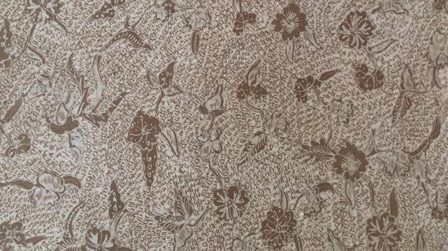 Traditional Indonesian batik fabric pattern with intricate floral and leaf motifs in brown tones.