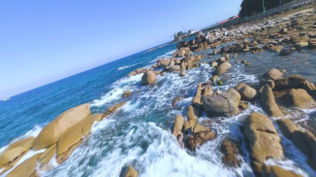 Dynamic fast-speed FPV drone shot flying low over heavy ocean waves in South Korea East Sea.