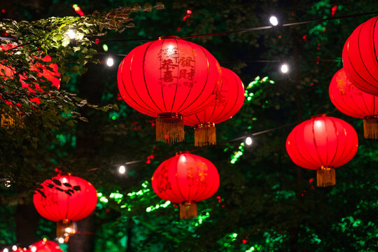 Red glowing Asian paper lanterns hanging outdoors amidst trees