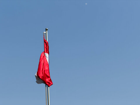 Indonesian Flag (Merah Putih) Waving at Half-Mast Against a Clear Blue Sky