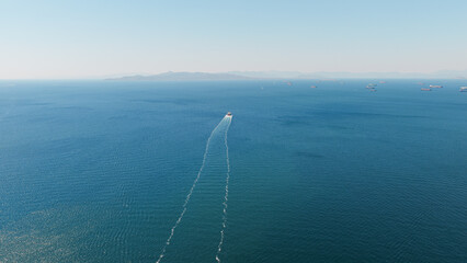 Fototapeta premium Cargo ship navigating vast blue ocean creating wake