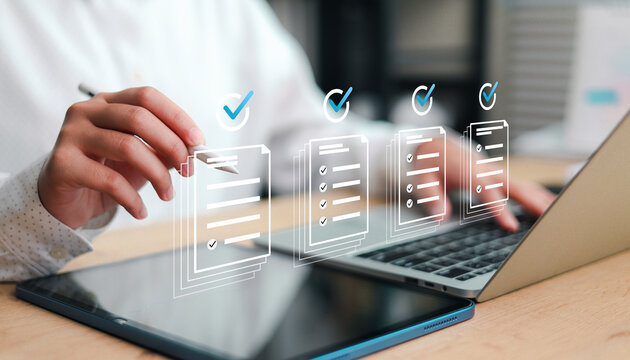 Close up man hand using stylus pen checking online document checklist on tablet with laptop. Professional businessman approving digital contract, survey or compliance report at office.