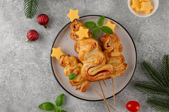 Puff pastry Christmas tree buns with cheese and ham on a plate. Christmas and New Year appetizer. Top view, copy space.
