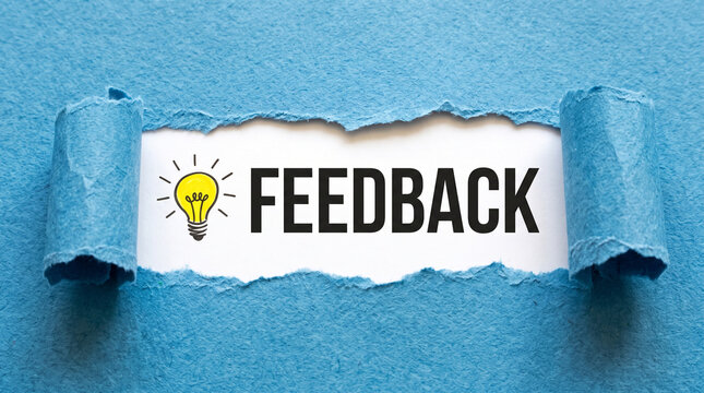 Conceptual image of the word feedback written on white paper revealed through a torn blue paper background with a lightbulb icon