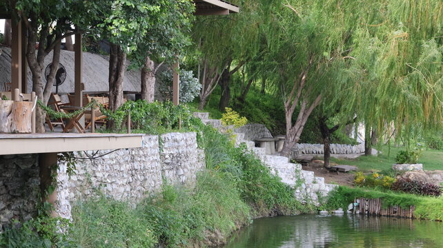 The image depicts a serene outdoor setting featuring a small body of water adjacent to a landscaped area