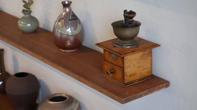 The image features a wooden shelf mounted on a white wall, displaying a collection of decorative items