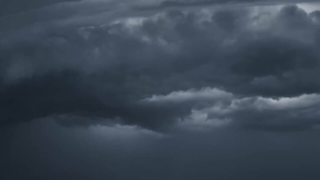 dark storm clouds rolling across the sky with lightning flashes illuminating turbulent cloud layers