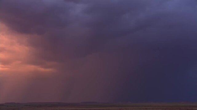 Dark storm clouds rolling across open plain at dusk with rain shafts and distant horizon