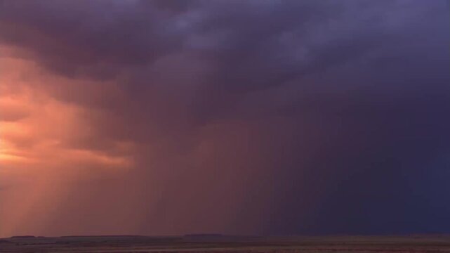 Dark storm clouds rolling across the open plain at dusk with a vivid lightning flash illuminating the horizon