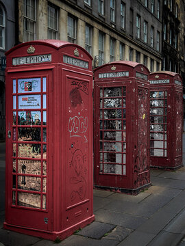 Three traditional red telephone booths on the Royal Mile in the old town of Edinburgh, Scotland.