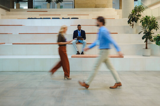 Business people walking and using tablet on office steps in motion blur