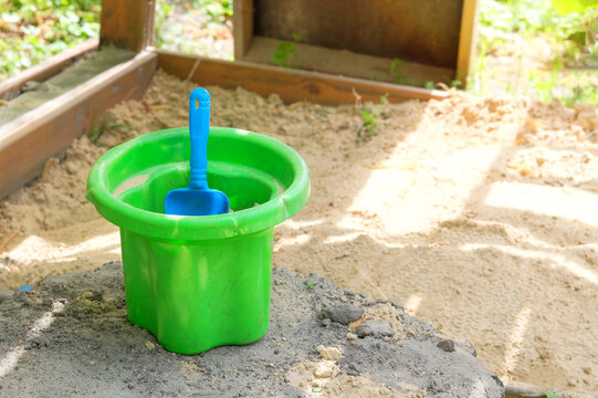 Children's toys in sandbox in summer. Bucket and spade in sand. Colorful plastic toys.