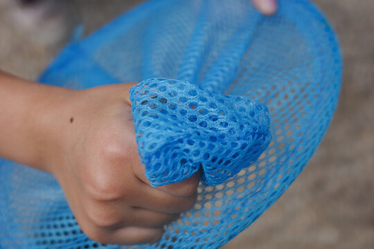 Close up of child's hand gripping a blue bug net tightly