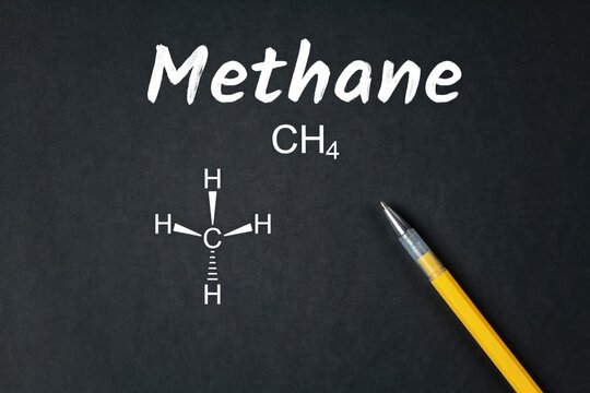 Methane chemical formula ch4 written on a black chalkboard surface with a yellow pen, down view of scientific notation