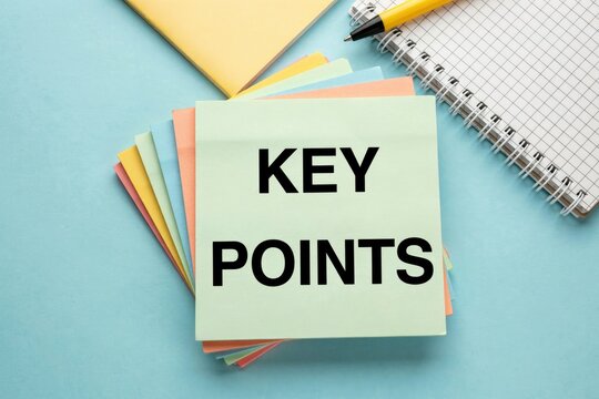 Top-down view of a light green sticky note with the text key points, stacked on colorful paper sheets with a spiral notebook and yellow pen