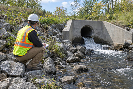 Drainage Engineer Inspecting Precast Concrete Outfall Headwall and Riverbank Riprap