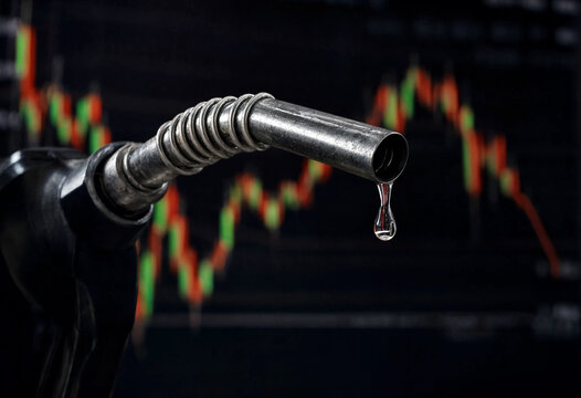 Closeup of a gasoline pump nozzle dripping fuel with stock market graph background