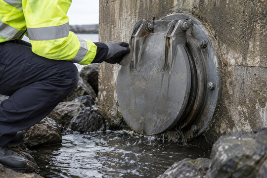 Drainage Engineer Inspecting Outfall Flap Valve for Backflow Prevention