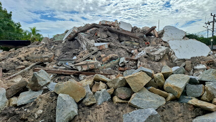 Massive heap of stone, concrete, and wooden debris from a demolished building under a cloudy sky. Ideal for disaster, renovation, and construction themes. © Bendy Moe
