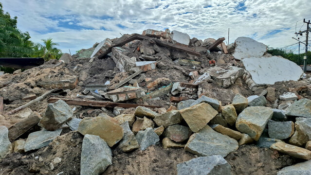 Massive heap of stone, concrete, and wooden debris from a demolished building under a cloudy sky. Ideal for disaster, renovation, and construction themes.