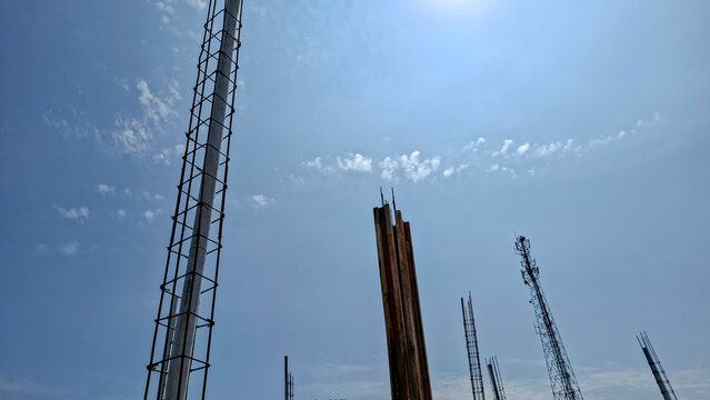 Low angle view of reinforced concrete column rebar and formwork on a construction site with a telecommunication tower in the background.