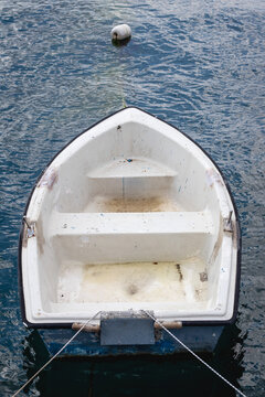 A fiberglass boat tied with a rope on the shore. A small boat or skiff on the blue sea, for recreational fishing. Conceptual idea for marine vessels. Top view, above, up. 