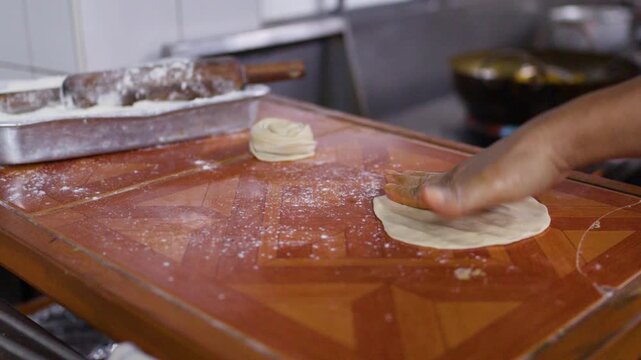 Chef Flattening and Shaping Roti Dough by Hand in Commercial Kitchen