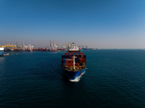 A Large Container Ship Loaded With Cargo Navigates Through The Blue Sea Toward The Industrial Terminal In Laem Chabang Chon Buri Thailand Under A Clear Sky