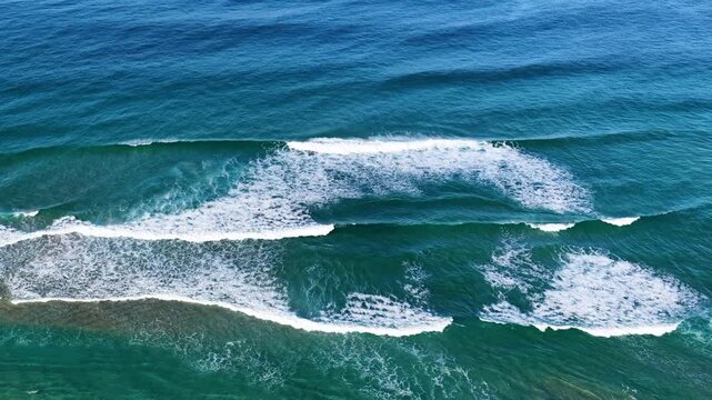 Aerial View of Turquoise Ocean Waves Breaking Along Coast