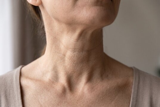 Close up of adult female neck showing natural skin lines and horizontal creases for skincare and dermatology concept