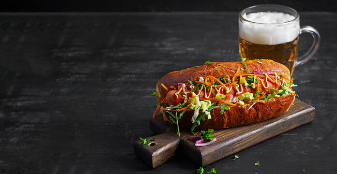 Gourmet Hot Dog with Fresh Vegetables and Beer on Dark Background. Oktoberfest food