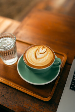 Remote work lifestyle, laptop screen showing photos with a cup of hot coffee on rustic wooden table.