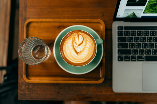 Top view of laptop computer and morning latte coffee cup on wooden table. Freelancer workspace concept.