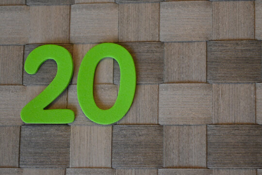 Green number twenty on woven wooden background
